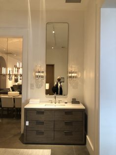 a bathroom with a large mirror above the sink and lights hanging on the wall behind it