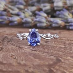 an oval tanzante ring with vines around it on a wooden table next to lavender flowers