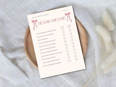 a wooden plate with a pink and white checklist on it next to some dry grass