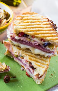 a cut in half sandwich sitting on top of a green cutting board