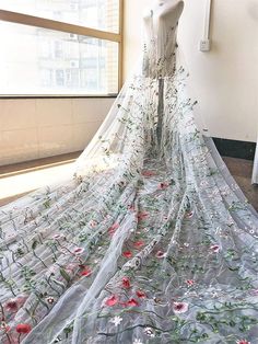 a dress on display in front of a window with sheer fabric and flowers all over it