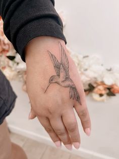 a person with a small tattoo on their left hand and a hummingbird tattooed on the wrist