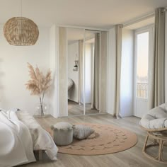 a bedroom with white walls and wood flooring has a large mirror on the wall