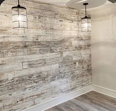 an empty room with wood paneling on the wall and ceiling fans hanging from the ceiling