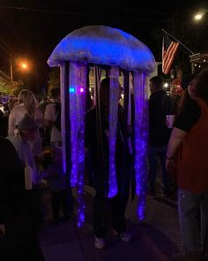 a group of people standing next to each other in front of a blue jellyfish tent