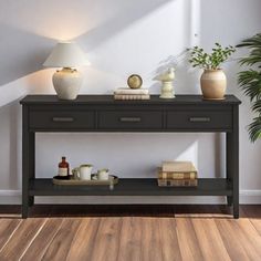 a table with some books and vases on it in front of a white wall