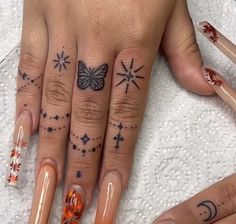 two fingers with tattoos on them and one has an orange nail polish varil, while the other has stars