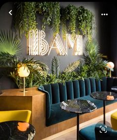 the interior of a restaurant with green plants on the wall and blue velvet seating area