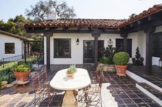 an outdoor dining area with potted plants on the table and chairs in front of it