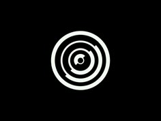 a black and white photo of a circular object with an arrow in the center on a dark background