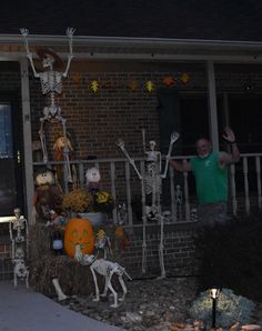 a man standing in front of a house decorated for halloween with skeletons and pumpkins