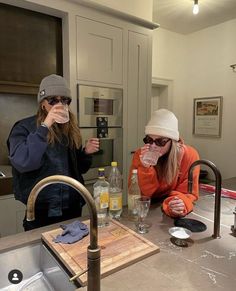 two women in the kitchen drinking from cups