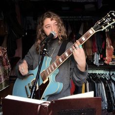 a woman singing into a microphone while holding a guitar