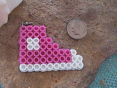 a penny sitting next to a pair of earrings made out of legos and beads