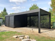 a black metal structure sitting on top of a grass covered field