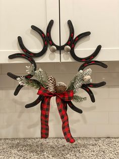 a reindeer antlers decoration hanging on the kitchen counter top with pine cones and evergreens