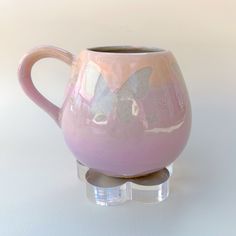 a pink coffee mug sitting on top of a glass stand