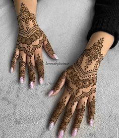 two hands with henna tattoos on them and one is showing the intricate design, while the