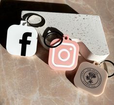 three different key chains are sitting next to each other on a marble counter top, one has a camera and the other has a pair of eyeglasses