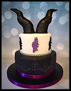 a three tiered cake with black and white frosting, decorated with purple decorations