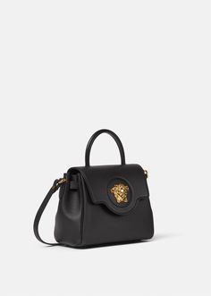 Crafted in Italy from premium leather, Versace's latest handbag is adorned with a Medusa plaque – the same décor that was discovered on the doors of the brand's first headquarters in Milan. The slouchy silhouette can be styled on the wrist or across the shoulder, featuring two detachable shoulderstraps: one leather and one chain. Luxury Shoulder Bag With Logo Hardware For Shopping, Luxury Shopping Satchel With Round Handle, Formal Tote Shoulder Bag With Logo Hardware, Luxury Tote Shoulder Bag With Logo Hardware, Luxury Travel Bags With Logo Hardware, Luxury Shopping Bags With Round Handle, Luxury Travel Bag With Logo Hardware, Luxury Shopping Bag With Round Handle, Luxury Satchel With Gold-tone Hardware For Shopping