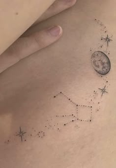 a woman's back with stars and a moon tattoo on her left side ribcage