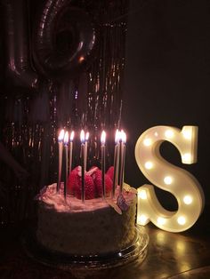 a birthday cake with lit candles and the letter s