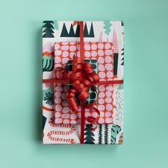 a present wrapped in colorful wrapping paper with a red bow on the top and green background