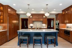 a large kitchen with an island in the middle and two stools at the center