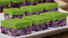 several pieces of green and purple dessert on a white plate