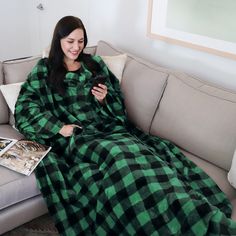 a woman sitting on a couch in a green and black checkered blanket