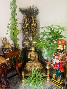 there are many statues and plants on the table in front of the wall, along with other decorative items