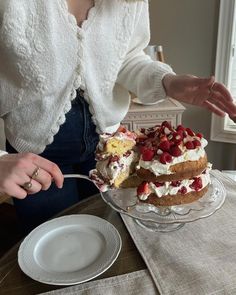 a woman is cutting into a cake on a table with plates and utensils