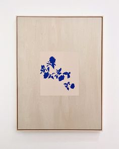 a blue flower on a white background in a wooden frame