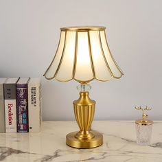 a gold lamp sitting on top of a white table next to a book case and some books