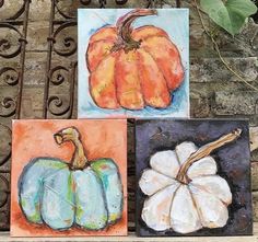 three paintings of pumpkins are displayed on a bench