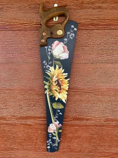 an old pair of scissors is hanging on a wooden wall with sunflowers and roses