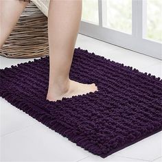 a person standing on top of a purple rug next to a basket and window sill