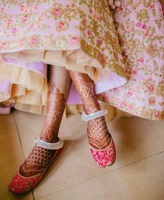 the legs and feet of a woman with henna on her feet, wearing pink shoes