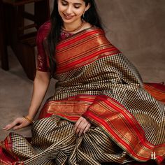 Indulge in the beauty of this black and beige Kanchipuram silk saree with a beautiful checked pattern. The saree features traditional style borders with red and orange stripes, adorned with gold zari intricacies. The delicately woven pallu adds to its elegant charm, making it a cherished addition to your collection.  Check out our collection of Kanchipuram silk sarees that are elegant and perfect for every occasion. Beige Kanchipuram Silk Saree, Latest Pattu Saree Designs, Latest Pattu Sarees, Kanchi Sarees, Latest Silk Sarees, Blouse Tops Designs, Kanjeevaram Sarees, Saree Ideas, Saree Blouse Styles