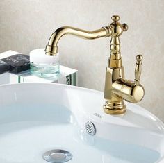 the faucet on the sink is gold and has water running from it's spout