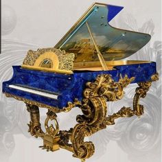 an ornate blue and gold grand piano with artwork on the top, in front of a white background