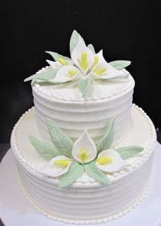 a three tiered cake with white and yellow flowers