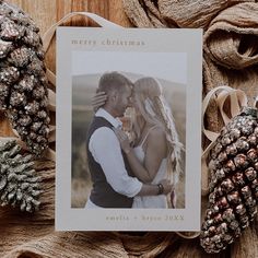 a christmas card with a couple kissing in front of pine cones