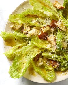 a white plate topped with lettuce covered in cheese and seasoning next to a fork