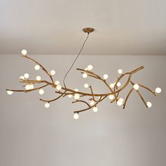 a chandelier made out of branches with lights hanging from the ceiling above it