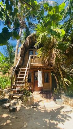 a small house on the beach with stairs leading up to it's second floor