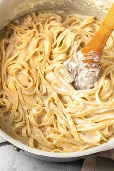 a wooden spoon in a pot filled with pasta