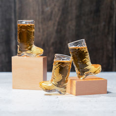 two glasses of beer sitting on top of wooden blocks with one glass in the middle