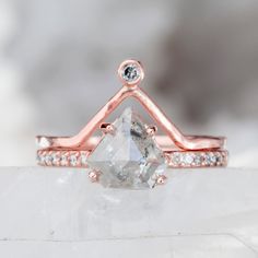 a white diamond ring sitting on top of a piece of rock with diamonds around it